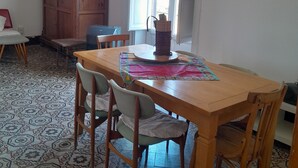 Ein Essbereich mit Holztisch, Stühlen, einem Musterfliesenboden, einer großen Holzkommode und einem Fenster mit Tageslicht.