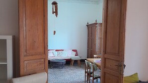 Ein offenes Durchgang zu einem Zimmer mit einem Bett, einem Holzschrank und einem Sessel.