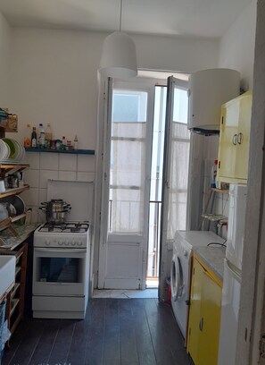 A compact kitchen with a gas stove, oven, and a washing machine.