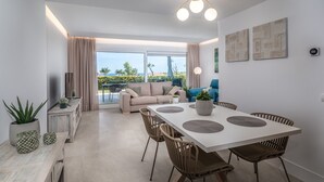 Un espace repas moderne avec une table blanche, des chaises marron et une vue sur l’extérieur.