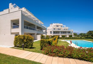 A modern two-story building with a swimming pool, surrounded by well-maintained gardens and a clear blue sky. - Emerald Green 2380 Golf & beach (San Roque)
