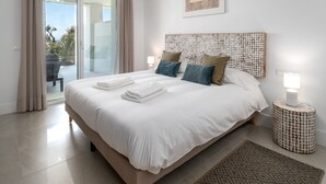 Une chambre moderne avec un grand lit, une tête de lit à motifs texturés et une vue sur l’extérieur grâce à une porte vitrée.