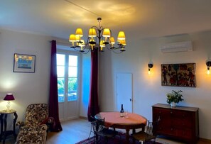 A dining area with a chandelier, a table, chairs, a cabinet, and a window with curtains.