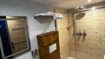 A bathroom with a wooden vanity, a white sink, a toilet, and a glass shower enclosure.