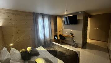 Une chambre d’hôtel moderne dotée d’un grand lit, d’un bureau avec une chaise, d’un téléviseur à écran plat fixé au mur et d’une fenêtre avec des rideaux.