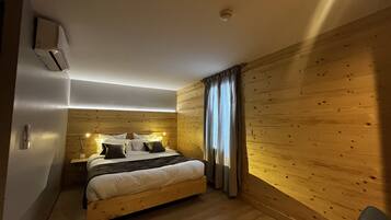 Quarto com cama de madeira, mesa de cabeceira e ar-condicionado fixado na parede.