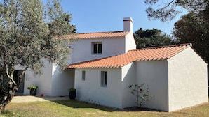 A two-story house with a red-tiled roof, white walls, and a small garden area with potted plants. - Villa TOUT CONFORT - Les pieds dans l'eau - 3 minutes walk from the sea (L'Épine)