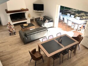 A modern living room with a fireplace, sofa, and dining area. - Fully Equipped Villa—direct access to the beach, just a 3-minute walk away, and close to shops (L'Épine)
