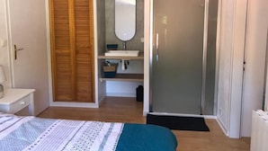A bedroom with a bed, wooden wardrobe, a bathroom with a mirror, and a shower. - Villa TOUT CONFORT - Les pieds dans l'eau - 3 minutes walk from the sea (L'Épine)
