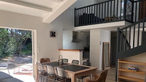 A spacious living area with a dining table, chairs, and a staircase leading to an upper level. - Villa TOUT CONFORT - Les pieds dans l'eau - 3 minutes walk from the sea (L'Épine)