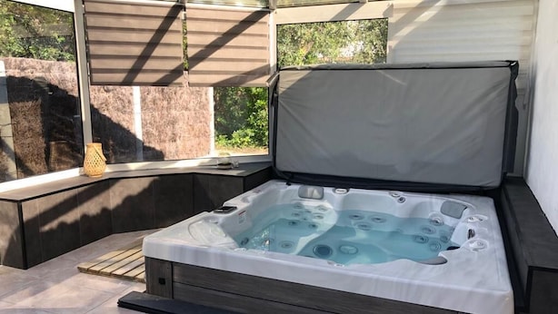 A hot tub in a covered outdoor area with a view of greenery. - Villa TOUT CONFORT - Les pieds dans l'eau - 3 minutes walk from the sea (L'Épine)