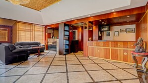 En lobby med en sort lædersofa, en receptionsdisk og en dekorativ statue.