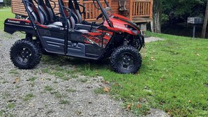 A 4x4 off-road vehicle parked in front of a wooden cabin with a porch.