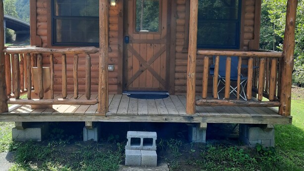 A wooden cabin with a porch, large windows, and a door.