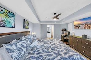 A bedroom with a bed, a ceiling fan, a dresser, and artwork on the walls.