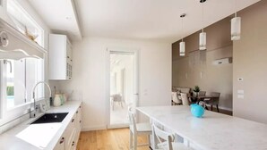 Une cuisine moderne avec des meubles blancs, un plan de travail en marbre et un plancher en bois.