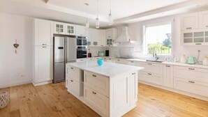 Une cuisine moderne avec des meubles blancs, des appareils en acier inoxydable et un îlot central.