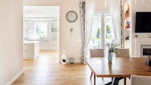 Un vaste espace de vie comprenant une table à manger en bois, une cheminée et une vue sur la cuisine et le jardin.