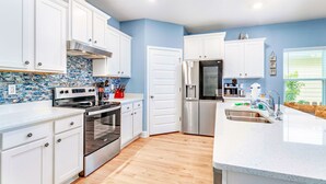 Una cocina moderna con armarios blancos, un refrigerador de acero inoxidable y salpicadero de azulejos.