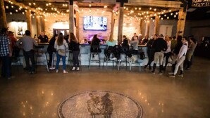 Un espace bar doté d’un sol en mosaïque circulaire, de poutres en bois et de guirlandes lumineuses.