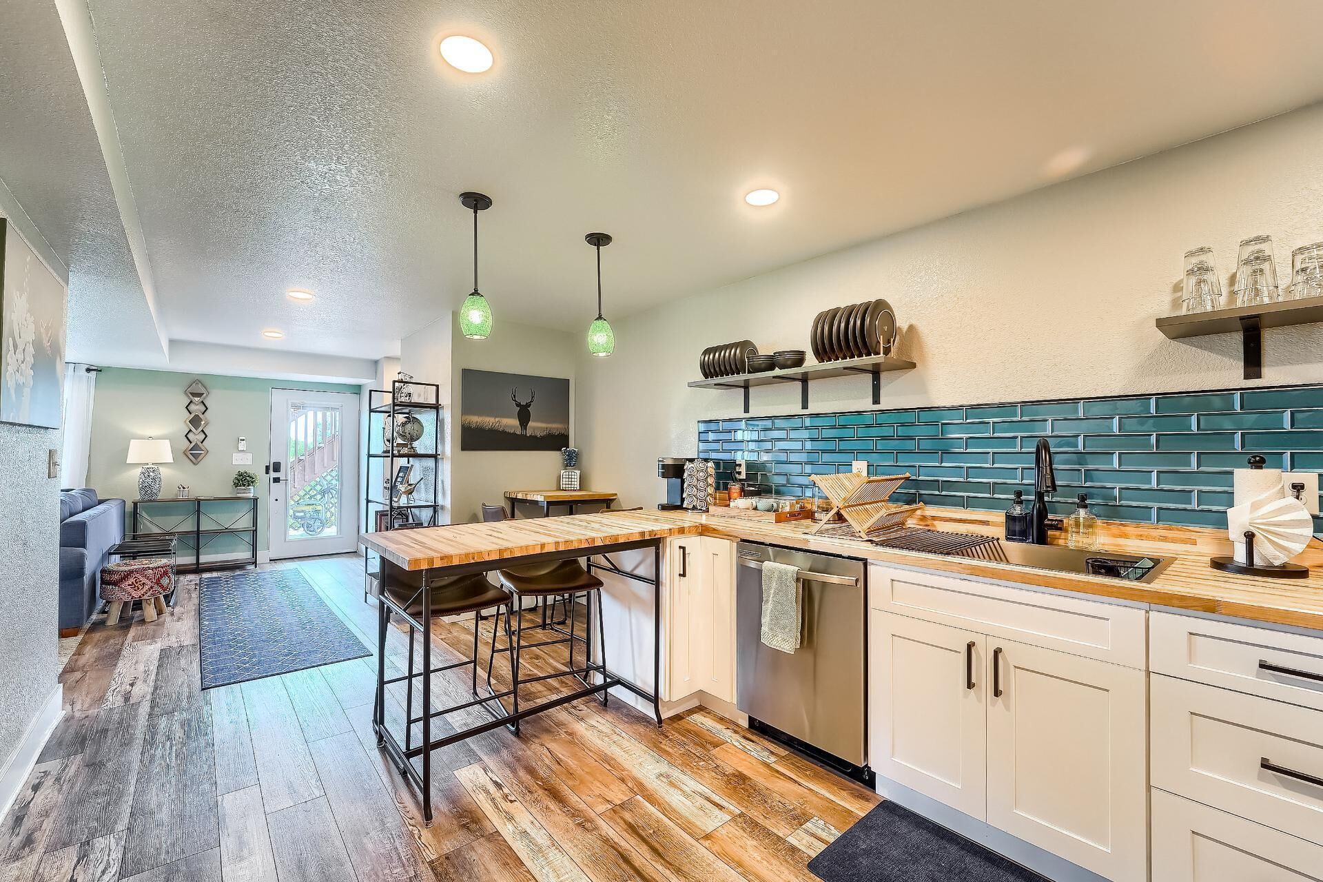 Una cocina moderna con una isla central, piso de madera y salpicadero de azulejos azules.