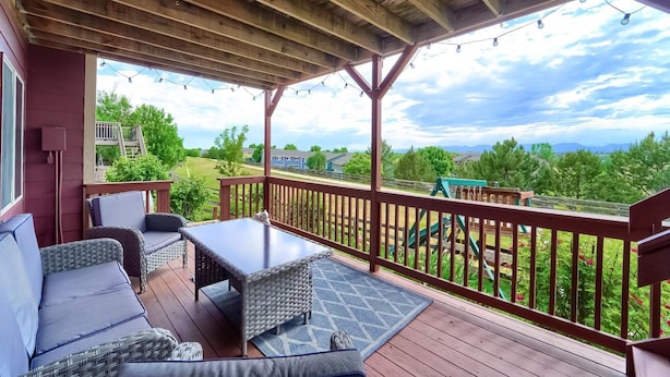 A covered deck with outdoor furniture, a wooden ceiling, and a view of a residential area with houses and greenery. - Grandview Hideaway - Vast views, walk to restaurants, disk golf, lots of privacy (Erie)