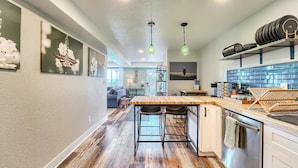 A modern kitchen with a wooden island, pendant lights, and a view into the dining area. - Grandview Hideaway - Vast views, walk to restaurants, disk golf, lots of privacy (Erie)