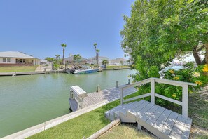 A waterfront property with a dock, a boat, and a grassy area with a bench.