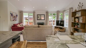 A modern living room with a sofa, TV, wooden coffee table, and a bookshelf. - Kirkstone Lodge (Windermere)