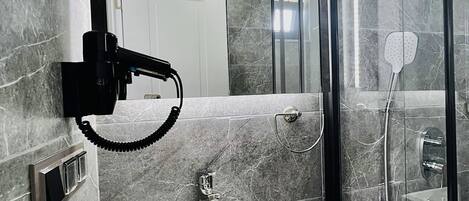 Un baño moderno con un lavabo blanco, un cabezal de ducha de mano y una ducha con mampara de vidrio.