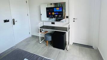 Ein modernes Hotelzimmer mit einem Bett, einem Schreibtisch mit Computer, einer Klimaanlage und einem Fernseher.