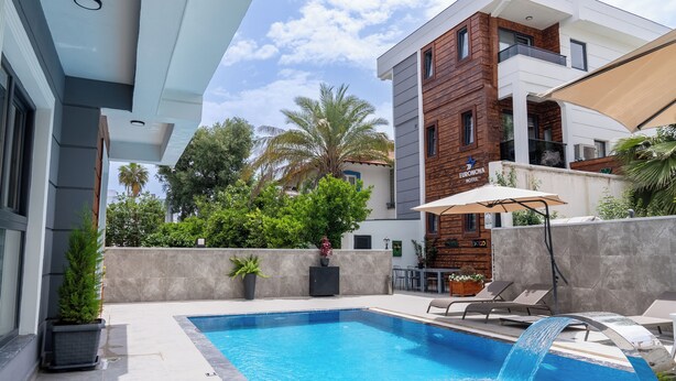 A modern hotel with a swimming pool, outdoor seating, and a view of palm trees. - EURONOVA HOTEL & SUITES (Kemer)