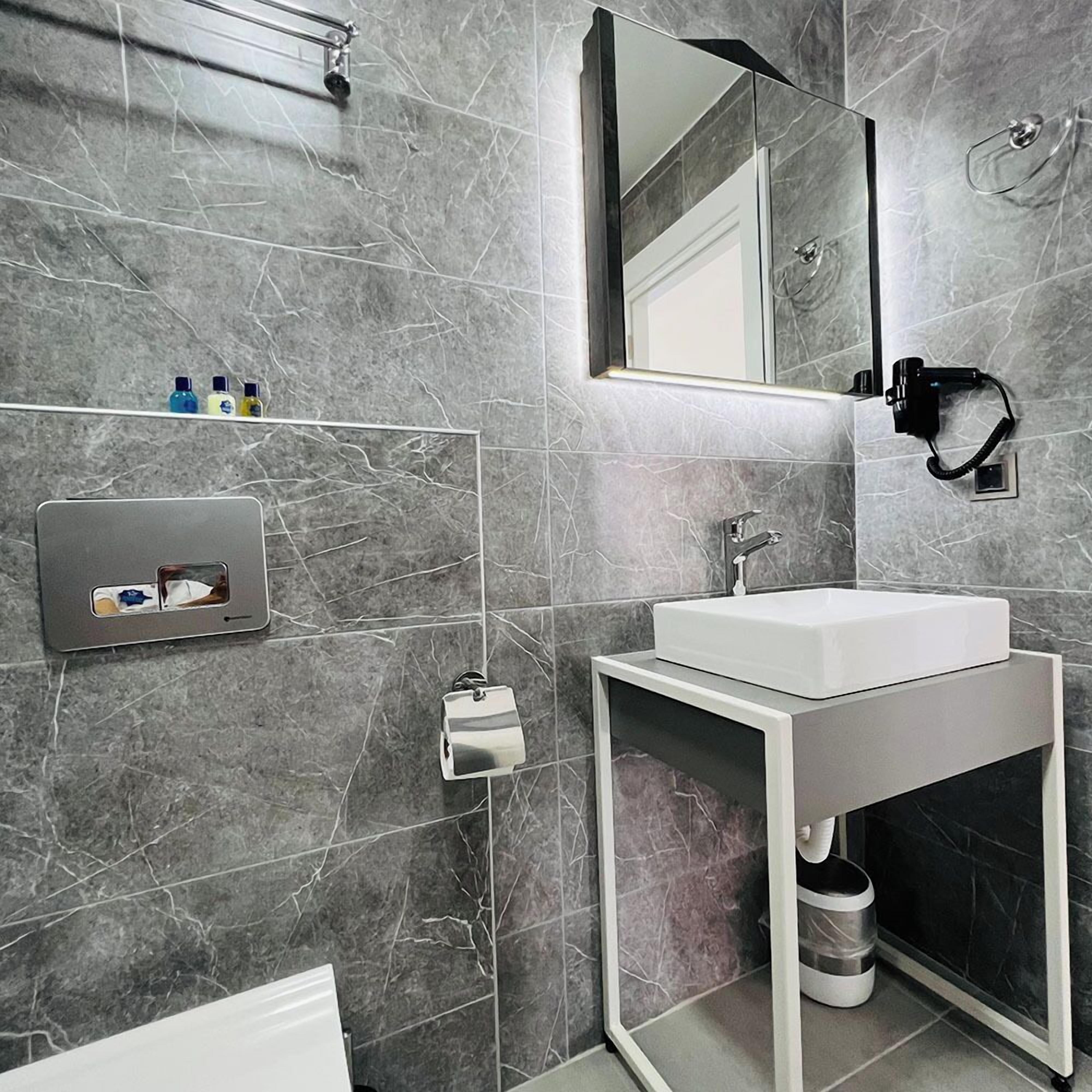 A modern bathroom with a white sink, a mirror, and a towel rack.