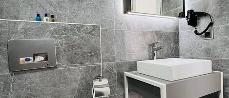 A modern bathroom with a white sink, a mirror, and a towel rack.