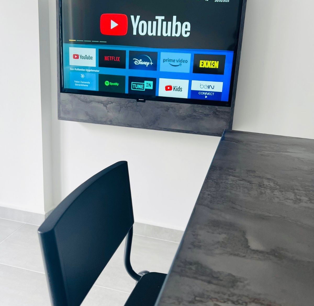 Un téléviseur à écran plat fixé au mur, affichant différentes plateformes de diffusion en continu.