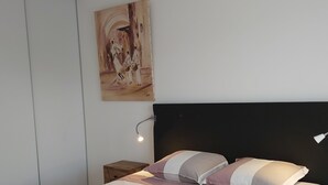 Un dormitorio con una cama, una mesita de noche, una lámpara de pared y un cuadro.