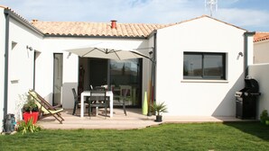 Una casa moderna con un patio, una parrilla y un ventanal grande.