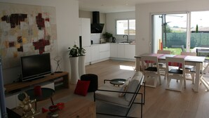 Una sala de estar moderna con un televisor de pantalla plana, un sofá y un comedor con una mesa y sillas.