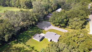 An aerial view of a residential area with two houses, a large tree, and a paved driveway. - The Horseman's Retreat (Ocala)