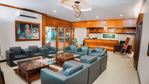 A hotel lobby with a reception desk, seating area, and a large framed artwork. - Hotel Palmyra Grand Inn (Kanayannur)