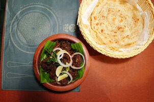 A table with a bowl of food and a basket of flatbread.