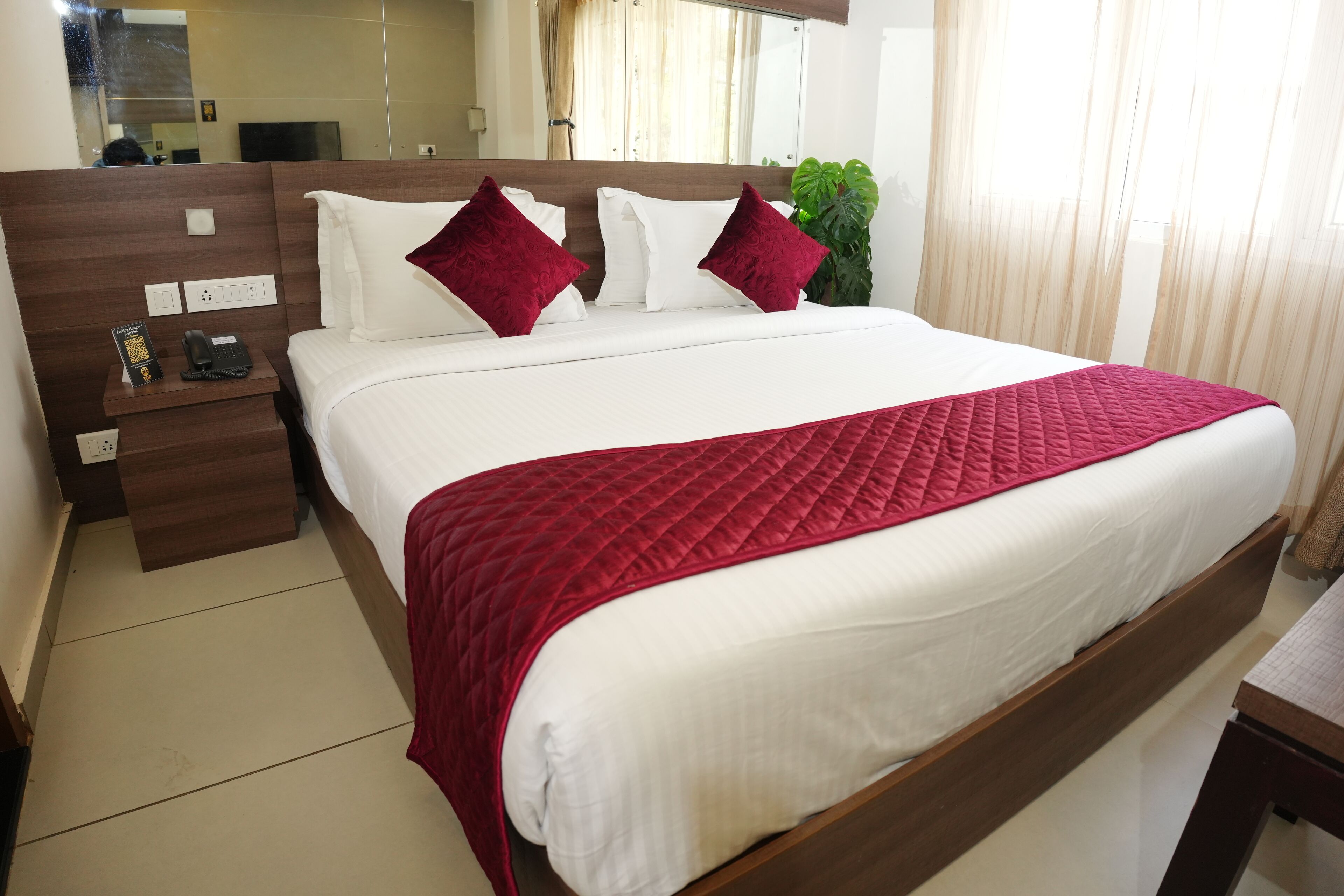 A neatly made bed with a red quilt, white pillows, and a wooden headboard.