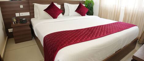 A neatly made bed with a red quilt, white pillows, and a wooden headboard.