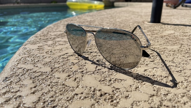 A pair of sunglasses on a textured surface near a pool. - AZ Sun & Serenity: 4BR home w/Heated Pool, BBQ Island, Prime location– Sleeps 12 (Surprise)