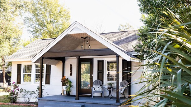 A house with a covered porch, two chairs, and a table.
