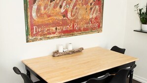 A dining area with a wooden table, black chairs, and a vintage Coca-Cola sign.