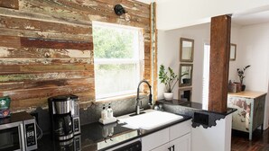 A modern kitchen with a wooden accent wall, a black countertop, and a window providing natural light.