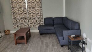 A living room with a grey sectional sofa, a wooden coffee table, and a small side table with a remote control.