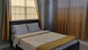 A neatly made bed with a headboard, a bedside table, and a lamp.