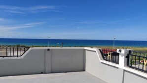 A rooftop terrace with a view of the ocean and a clear sky.